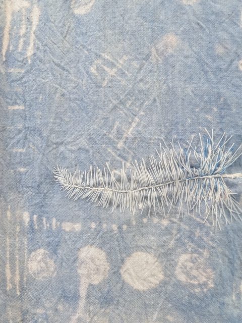 Detail of sewn feathers on dyed and bleached calico